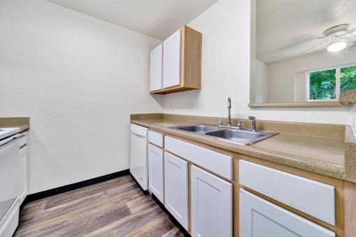 a kitchen with white cabinets and a sink and a window