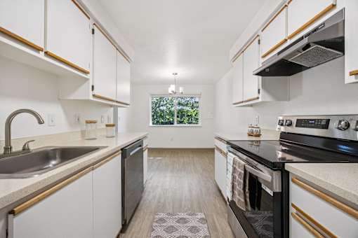 A modern kitchen with white cabinets and a black stove top oven.