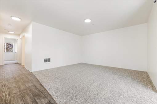 A room with a carpeted floor and wooden flooring by the door.