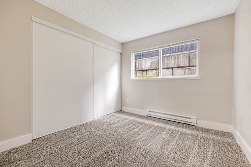 A room with a carpeted floor and a window.