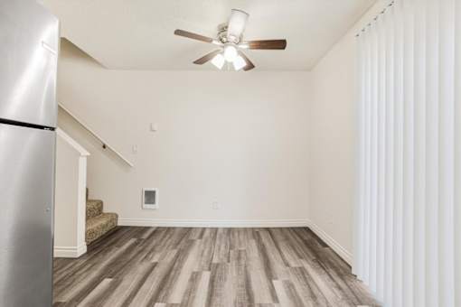 A room with a ceiling fan and wooden flooring.