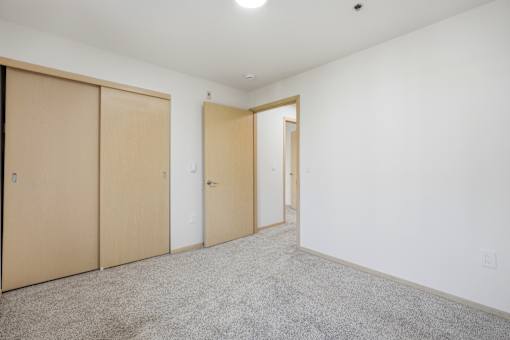 A room with a carpeted floor and three doors.