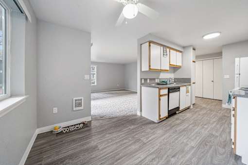 A modern kitchen with white cabinets and a wooden floor.