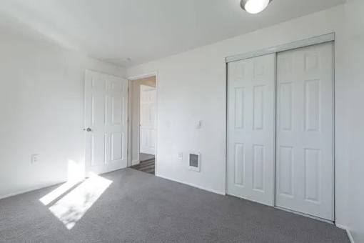 A room with white walls and a grey carpet.