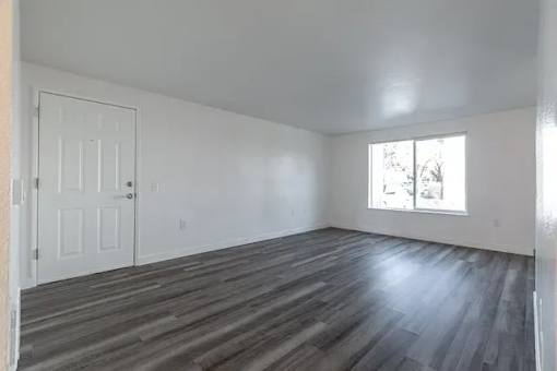A room with a white door and a window with a view of trees outside.