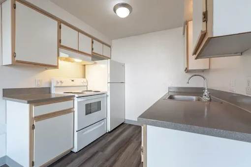 A kitchen with white appliances and wooden cabinets.
