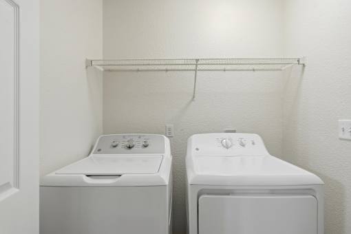 Two white front loading washing machines in a small laundry room.