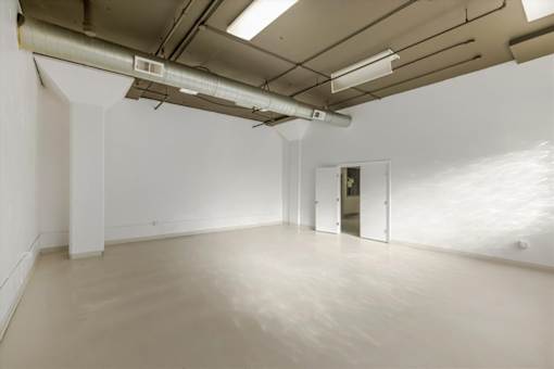 A large empty room with white walls and a concrete floor.
