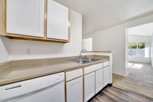 an empty kitchen with white cabinets and a sink