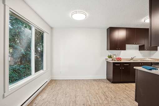A kitchen with brown cabinets and a window overlooking greenery.