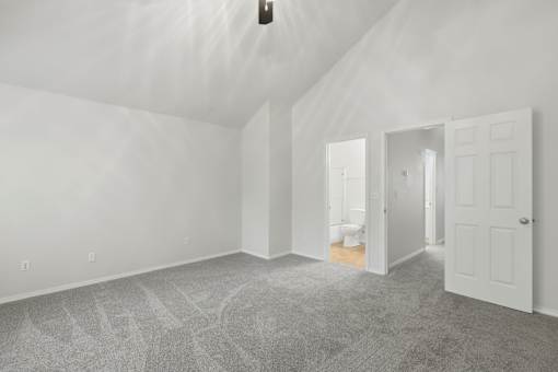 A white room with a carpeted floor and a door on the right side.