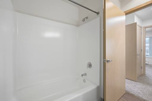 A white bathroom with a tub and a door.
