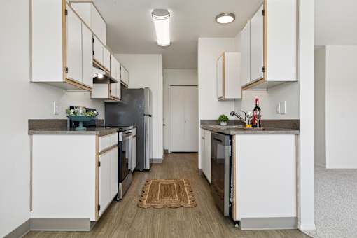 A kitchen with white cabinets and a wooden floor.