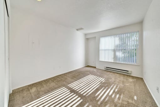 the spacious living room of an apartment with a large window