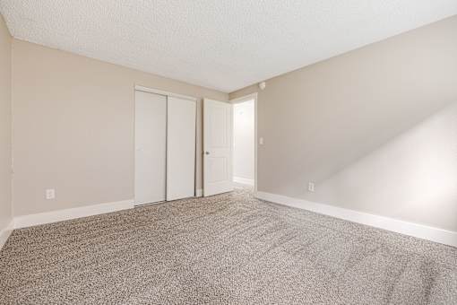 A room with carpeted floor and two doors.