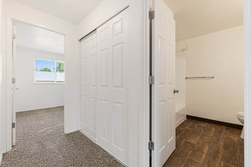 A white door is open to a room with a wooden floor.
