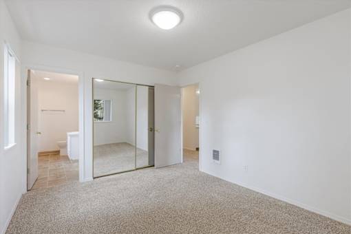 A spacious room with a carpeted floor and a large mirror on the wall.