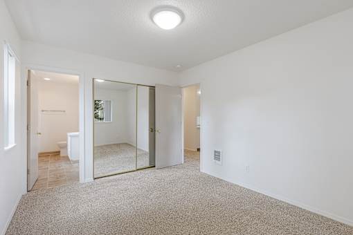 A spacious room with a carpeted floor and a mirror on the wall.