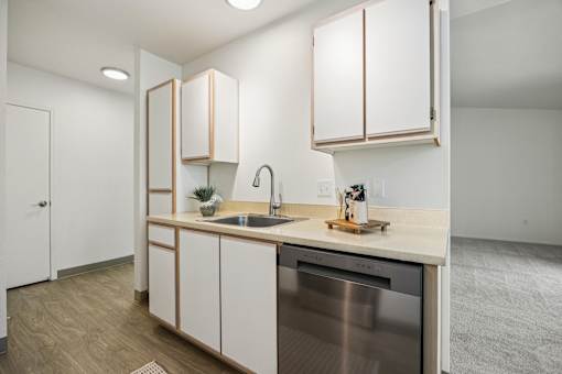 A kitchen with a stainless steel dishwasher and wooden cabinets.