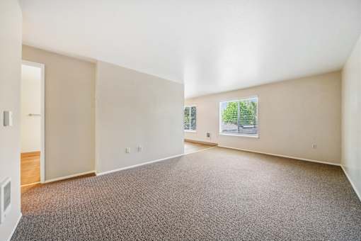 A large empty room with a carpeted floor and a window.