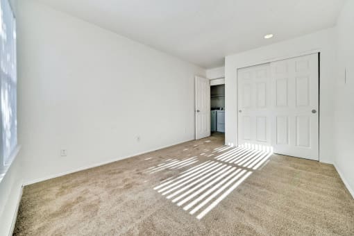 an empty living room with carpet and a door to a kitchen