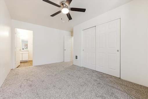 A room with a ceiling fan and carpeted floor.