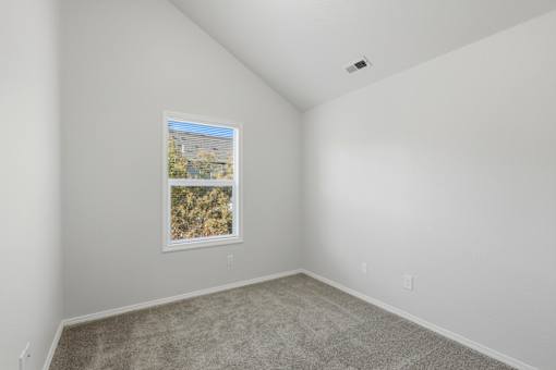 A room with a picture frame on the wall and carpeted floor.