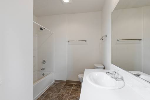 A white bathroom with a toilet, sink, and shower.