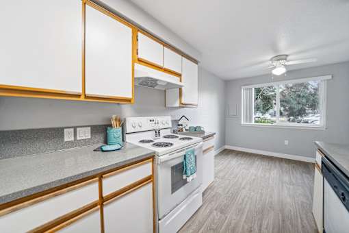 A kitchen with white cabinets and a white stove top oven.