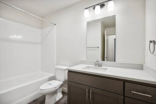 A white toilet sits in a bathroom next to a sink and a mirror.