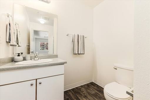 A white bathroom with a toilet, sink, and mirror.