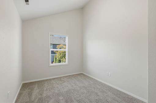 A room with a window and a picture frame on the wall.