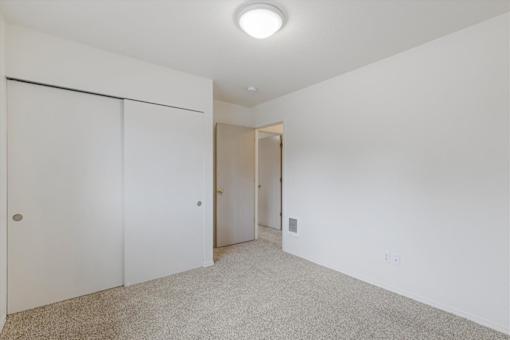 A white room with a carpeted floor and a door on the left.