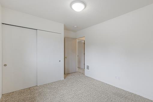 A white room with a carpeted floor and a sliding door.