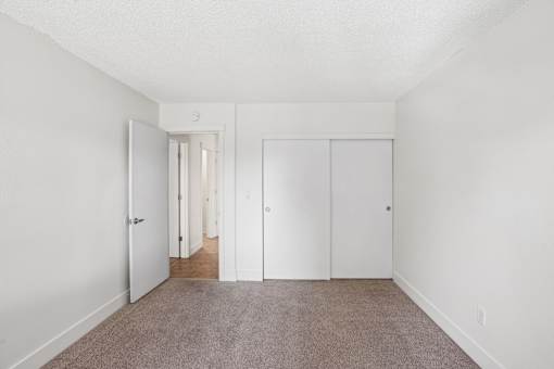 A long hallway with white doors and carpeted flooring.