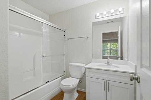 A white bathroom with a toilet, sink, and shower.
