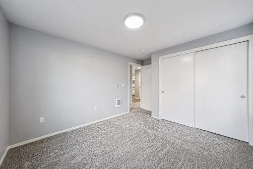 A spacious room with grey carpeting and white walls.