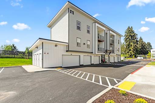 A modern two-story apartment building with a parking lot in front.