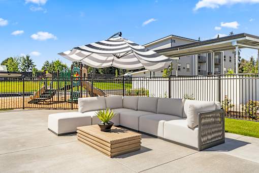 A white couch is placed on a patio with a wooden coffee table in front of it.