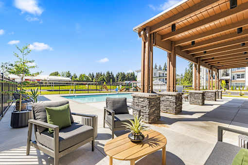 A wooden table with a potted plant on it sits in the middle of a patio.
