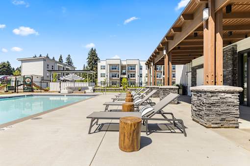 A pool area with sun loungers and a stone pillar.