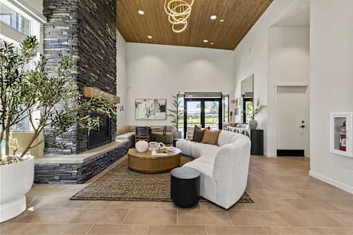 A modern living room with a stone fireplace and a large window.