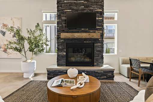 A living room with a stone fireplace and a flat screen TV mounted above it.