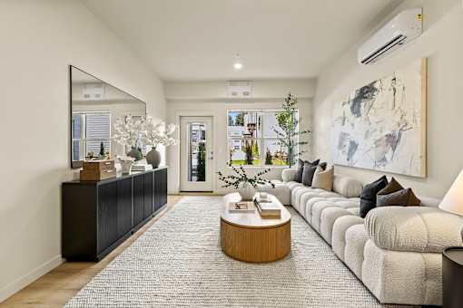 A modern living room with a large mirror, a coffee table, and a large painting on the wall.
