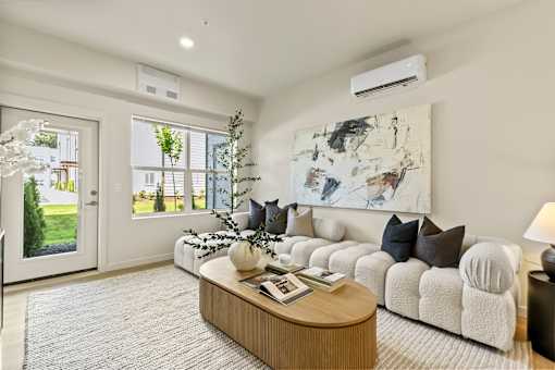 A living room with a white couch, a coffee table, and a large window.