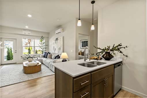 A modern kitchen with a large island and a living area with a couch and a coffee table.