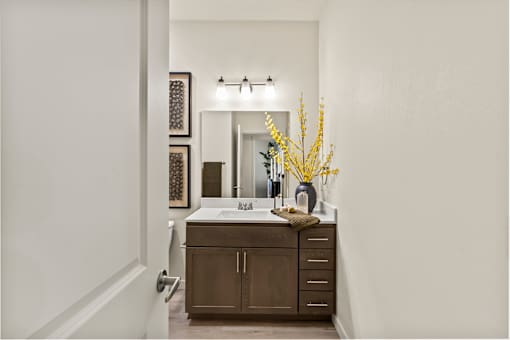 A bathroom with a brown vanity and a white sink.