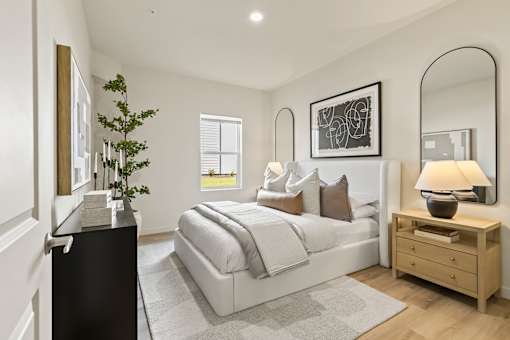 A well-lit bedroom with a large bed, a nightstand, and a mirror.