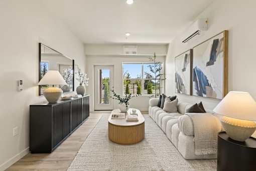 A modern living room with a large couch, a coffee table, and a large painting on the wall.