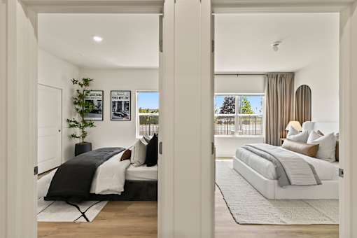 A bedroom with two beds and a window with curtains.